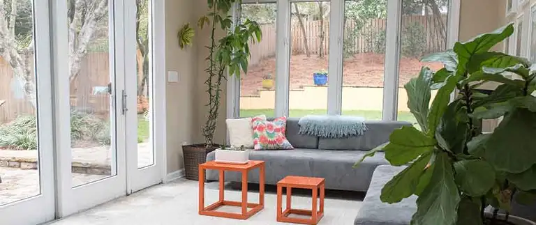 Sunroom construction, bright finished sunroom with large windows, plants, and modern seating