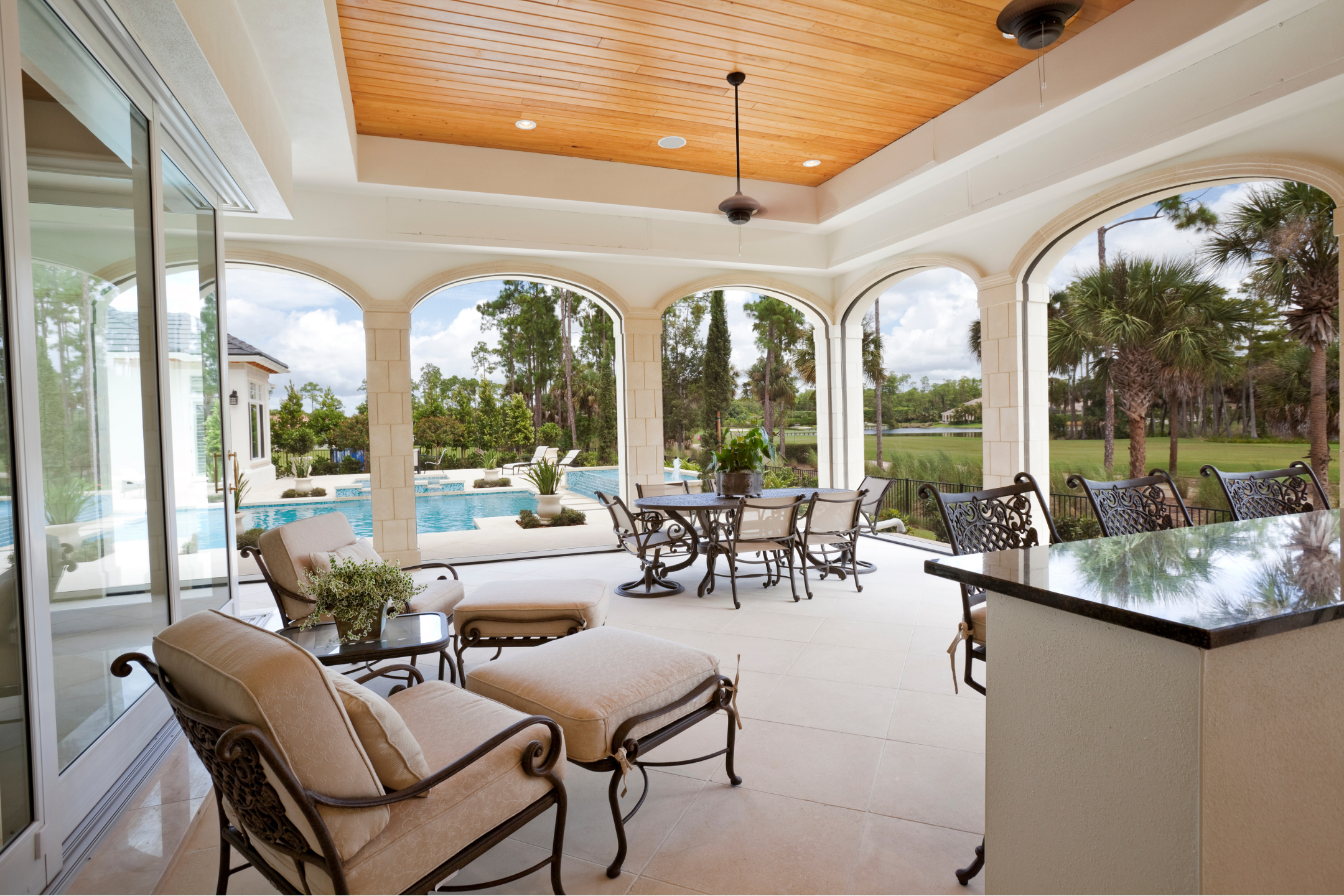 Covered lanai with arched columns and poolside seating