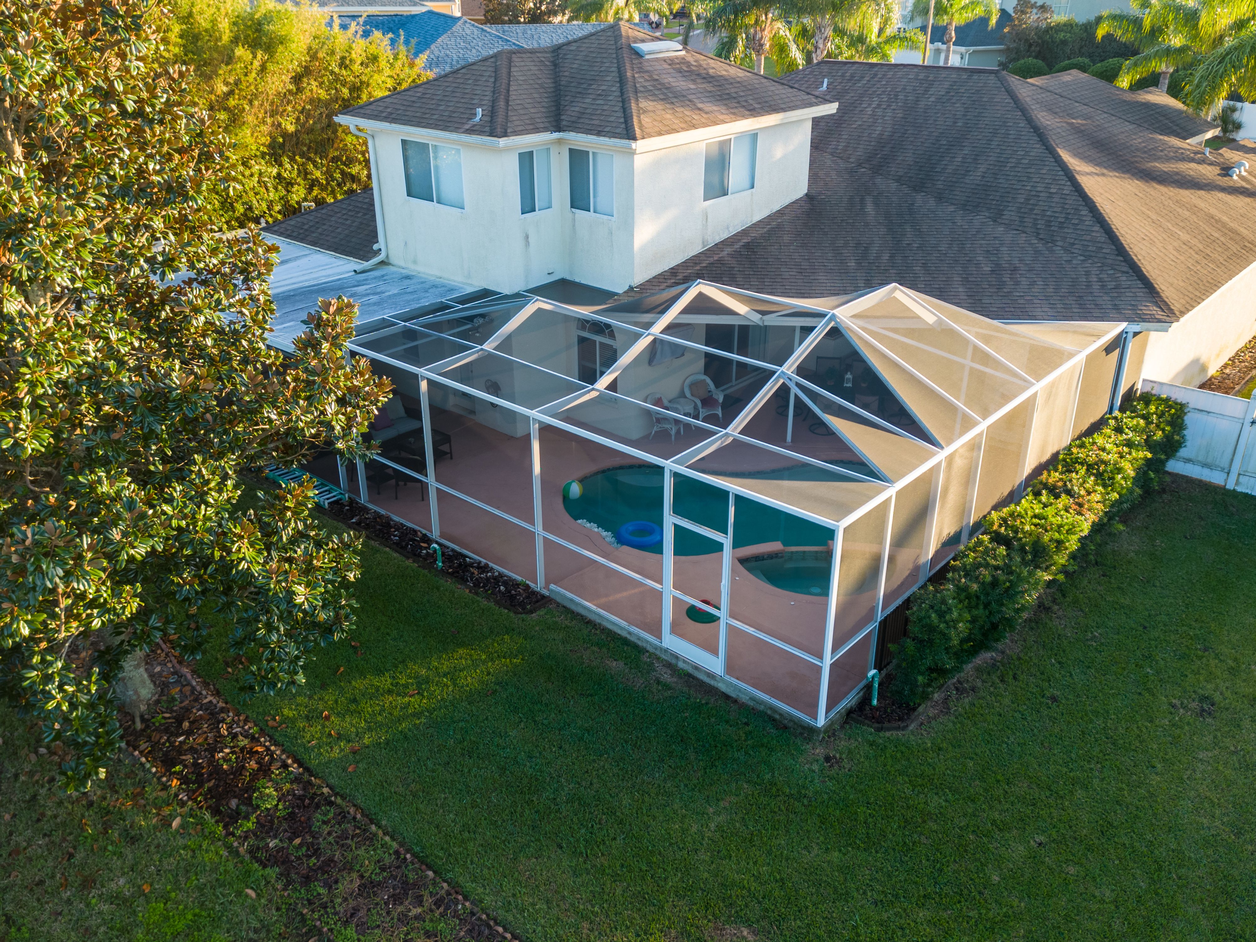 Side view of a screened pool enclosure connected to a residential home