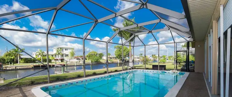Pool cages in Florida, screened enclosure over a swimming pool with waterfront view